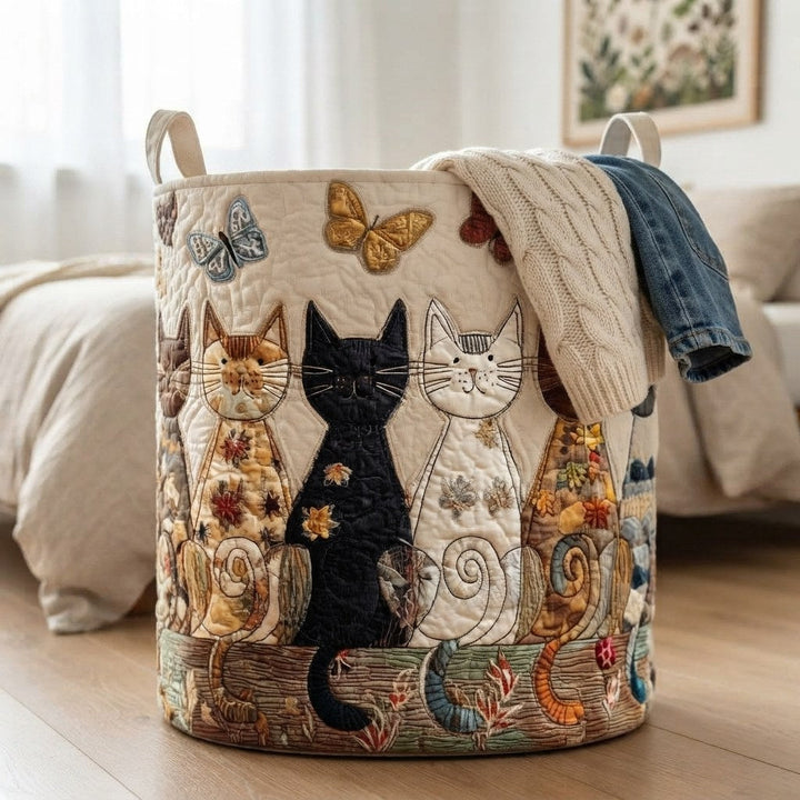 Panier posé au pied d'un lit, débordant d'un pull torsadé crème et d'un jean, avec ses chats brodés bien visibles. 4