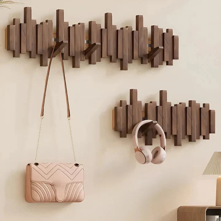 Deux portemanteaux en bois foncé sur un mur beige, portant un sac rose à chaînette et un casque 9