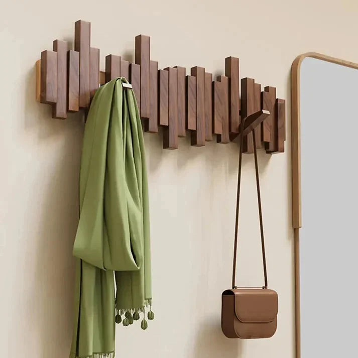 Portemanteau en bois foncé fixé au mur, avec une écharpe verte et un petit sac marron suspendus 1