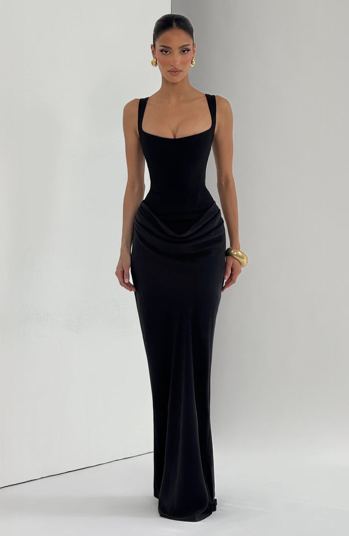 Robe longue noire portée de face devant un fond clair, silhouette fourreau avec drapé marqué à la taille. 17