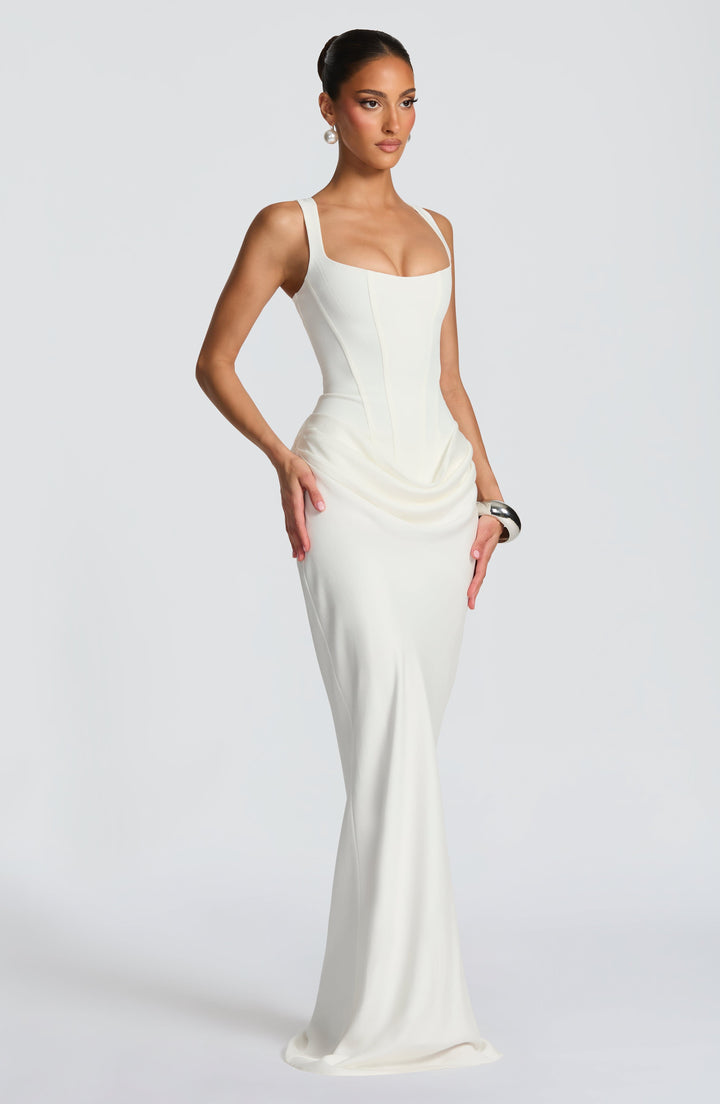 Robe blanc cassé vue de trois quarts, mains posées sur les hanches, drapé latéral et jupe longue fluide. 9