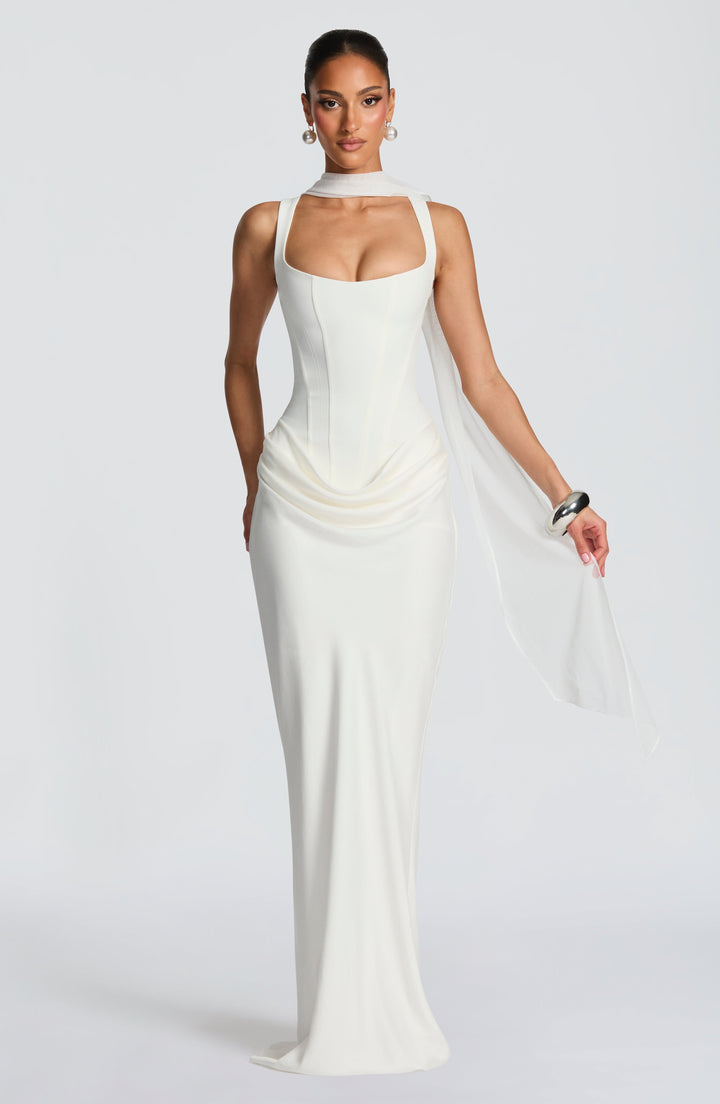 Robe blanc cassé portée avec une longue écharpe en voile légère nouée autour du cou et tombant sur le bras. 11
