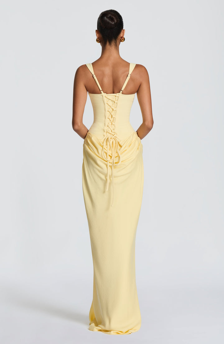 Vue de dos de la robe jaune pâle, avec lacets croisés dans le dos, bretelles réglables et drapé sur le bas du dos. 32