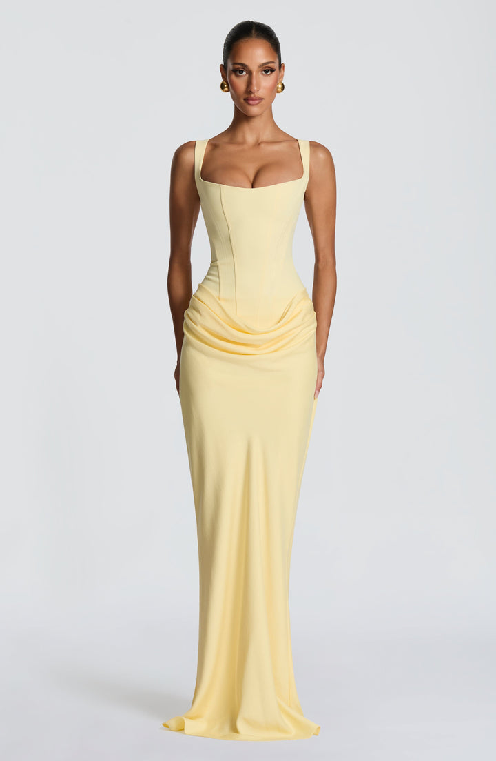 Robe jaune pâle vue de face en pied, avec corset à encolure carrée, drapé plissé aux hanches et jupe longue ajustée. 31