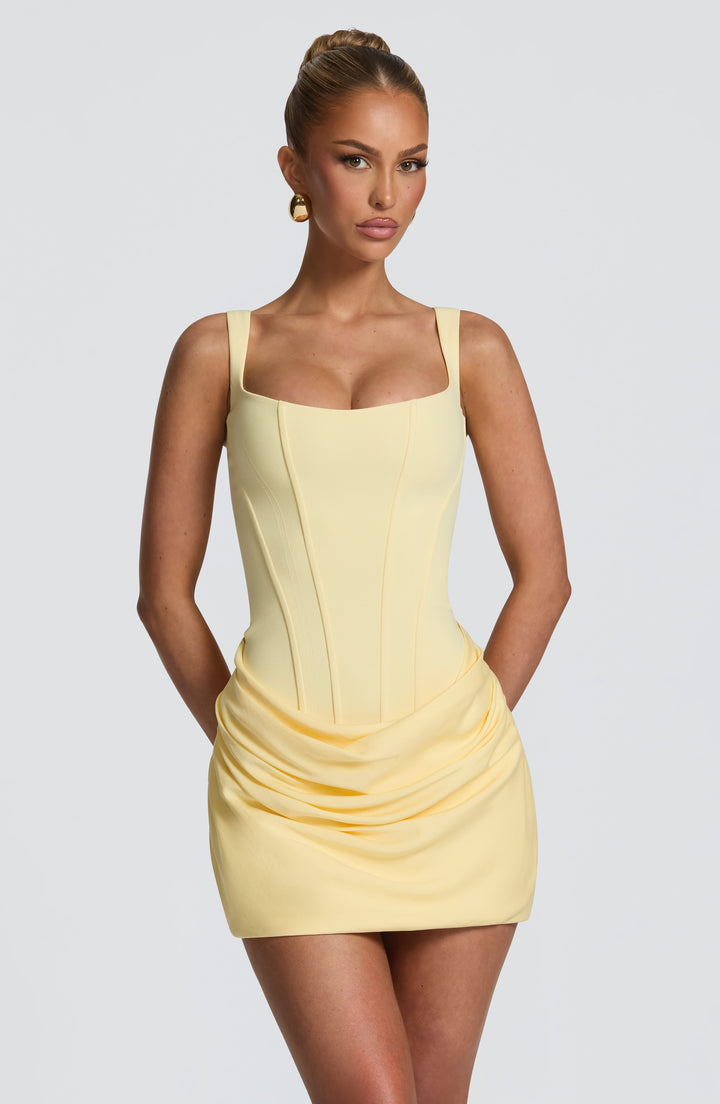 Robe jaune pâle portée de face, gros plan sur le buste corset à fines coutures et sur le drapé de la jupe. 25