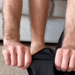 Gros plan de mains qui enfilent un bas noir sur une jambe, assis sur un canapé 5