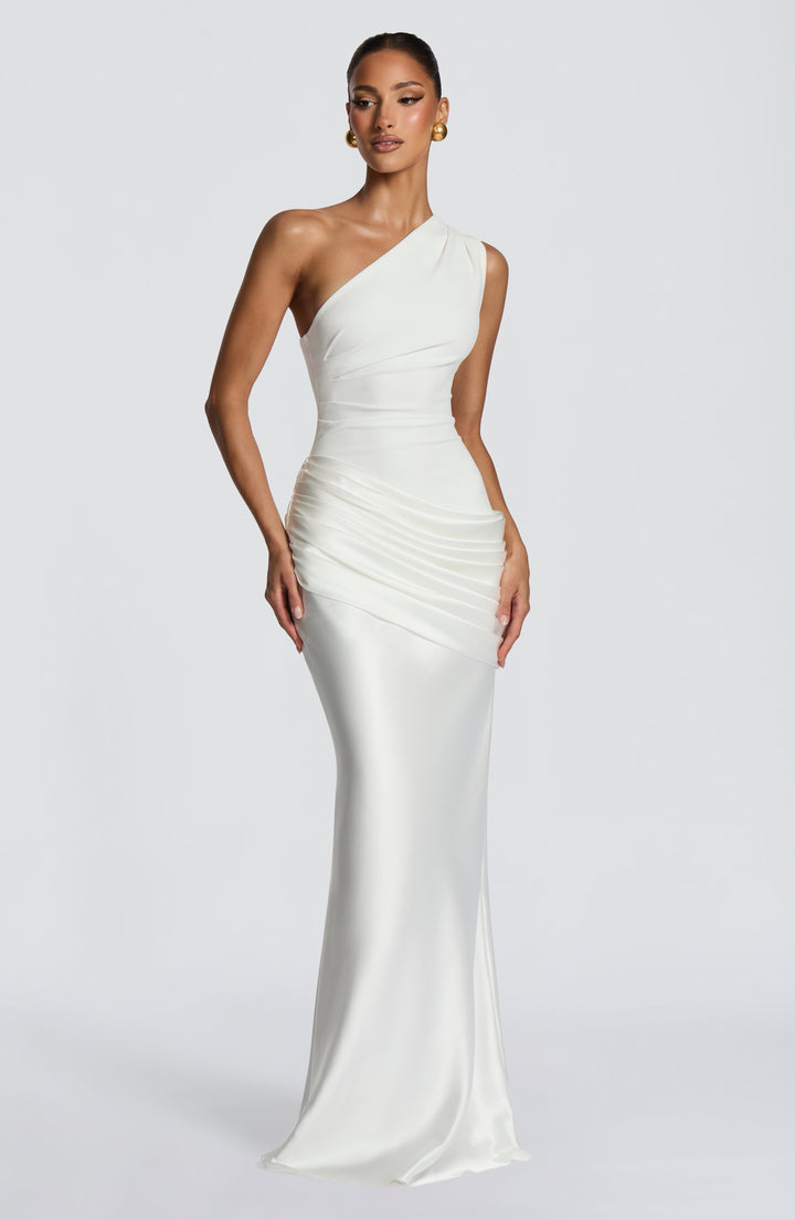 Robe blanche asymétrique portée par un mannequin, main sur la hanche, buste en crêpe, drapé plissé et jupe satinée. 21