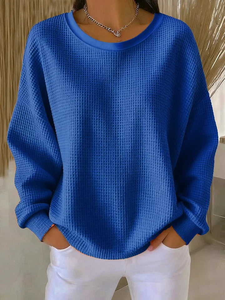 Pull gaufré bleu roi à col rond, porté par un modèle avec un pantalon blanc et un collier argenté. 5