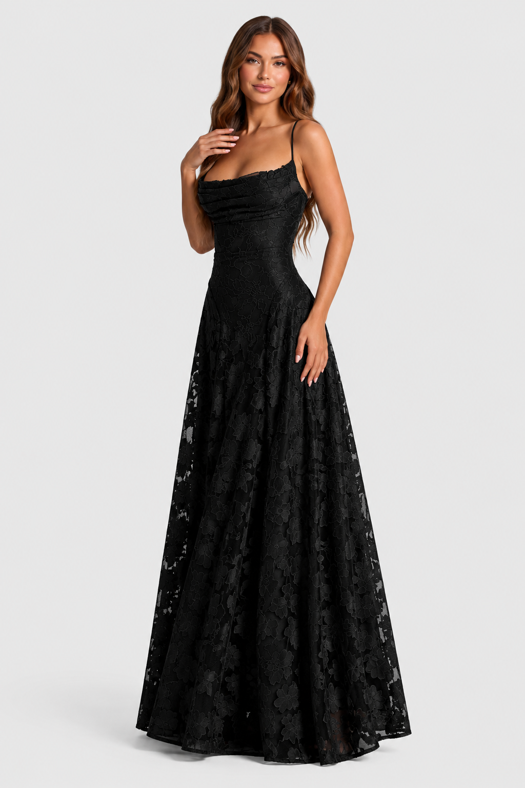 Robe noire en dentelle florale portée de trois quarts, une main posée sur la poitrine, encolure drapée et jupe évasée transparente. 11