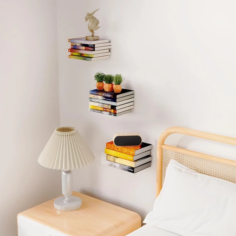 Trois piles de livres colorés fixées au mur d'une chambre, près d'un lit et d'une lampe de chevet, avec plantes, statuette et enceinte. 6