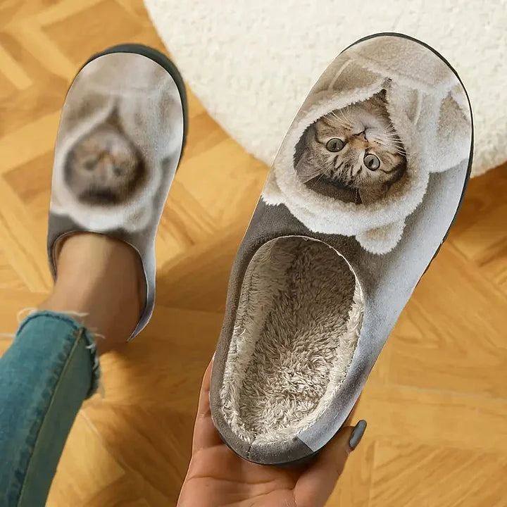 Vue plongeante sur une paire de chaussons, un pied enfilé et l'autre tenu à la main, doublure peluche visible. 2