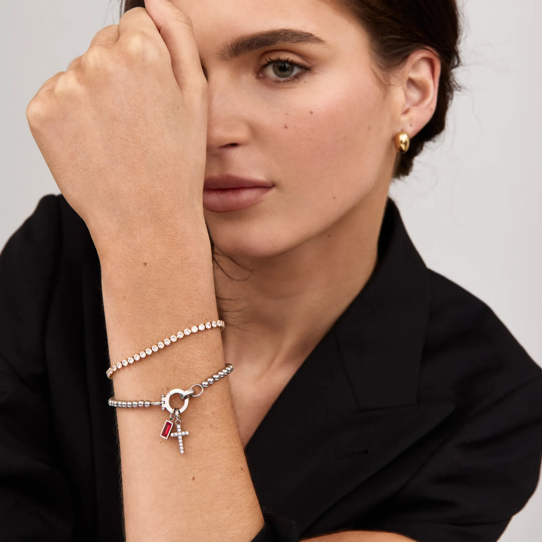 Portrait d'une femme en veste noire portant le bracelet argenté à perles, croix et pierre rouge, avec un bracelet de strass. 6