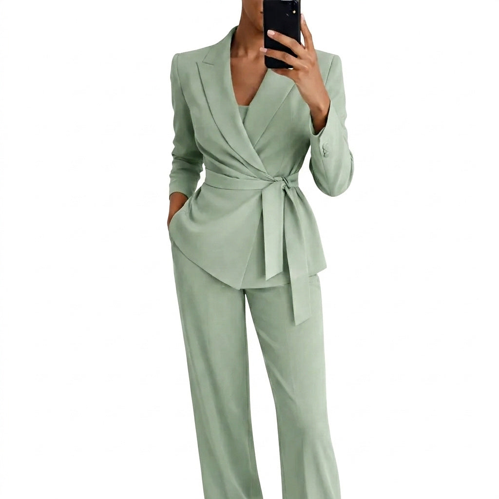 Femme en tailleur vert d'eau, blazer croisé noué à la taille et pantalon ample, photographiée de face en selfie miroir. 1