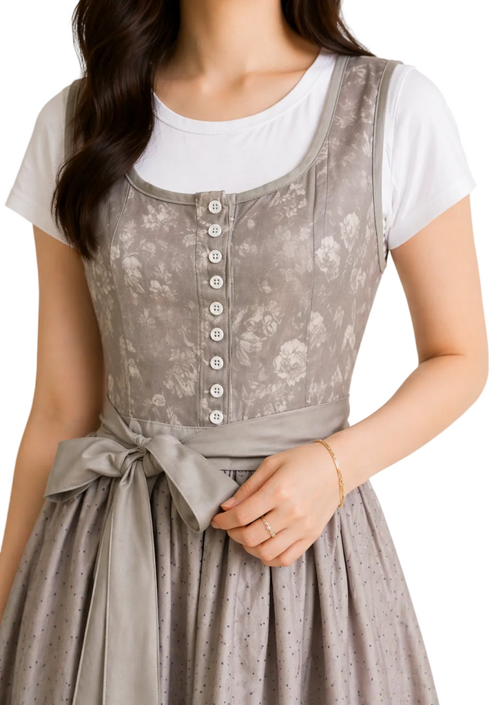 Gros plan sur le corsage gris à motif floral, ses boutons nacrés sur le devant et le nœud de ceinture, porté sur un t-shirt blanc. 1