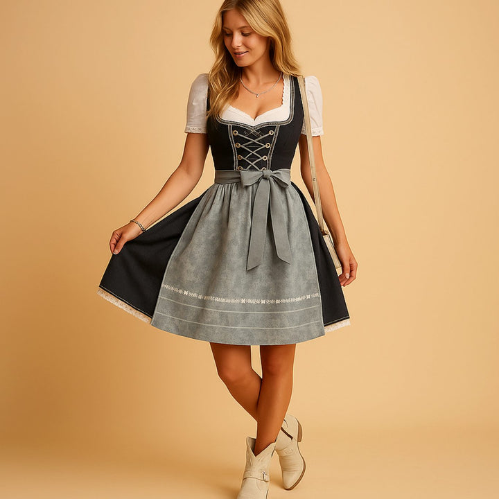 Mannequin en pied, robe dirndl à corsage sombre lacé et tablier gris, jupe légèrement relevée d'une main, avec bottines claires. 3