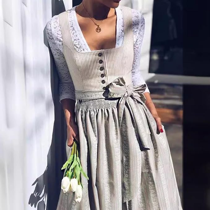 Dirndl porté avec un chemisier en dentelle blanche, mannequin appuyée contre un mur clair et tenant des tulipes blanches. 2
