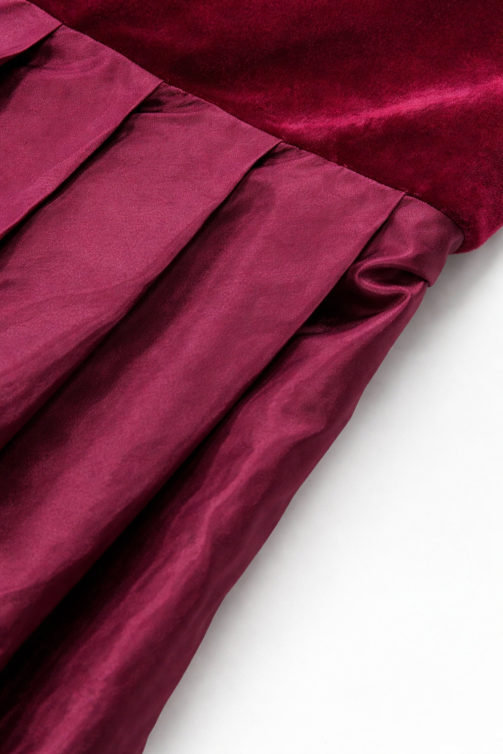 Gros plan sur la couture de taille entre le velours du corsage et la jupe plissée à l'aspect satiné. 2