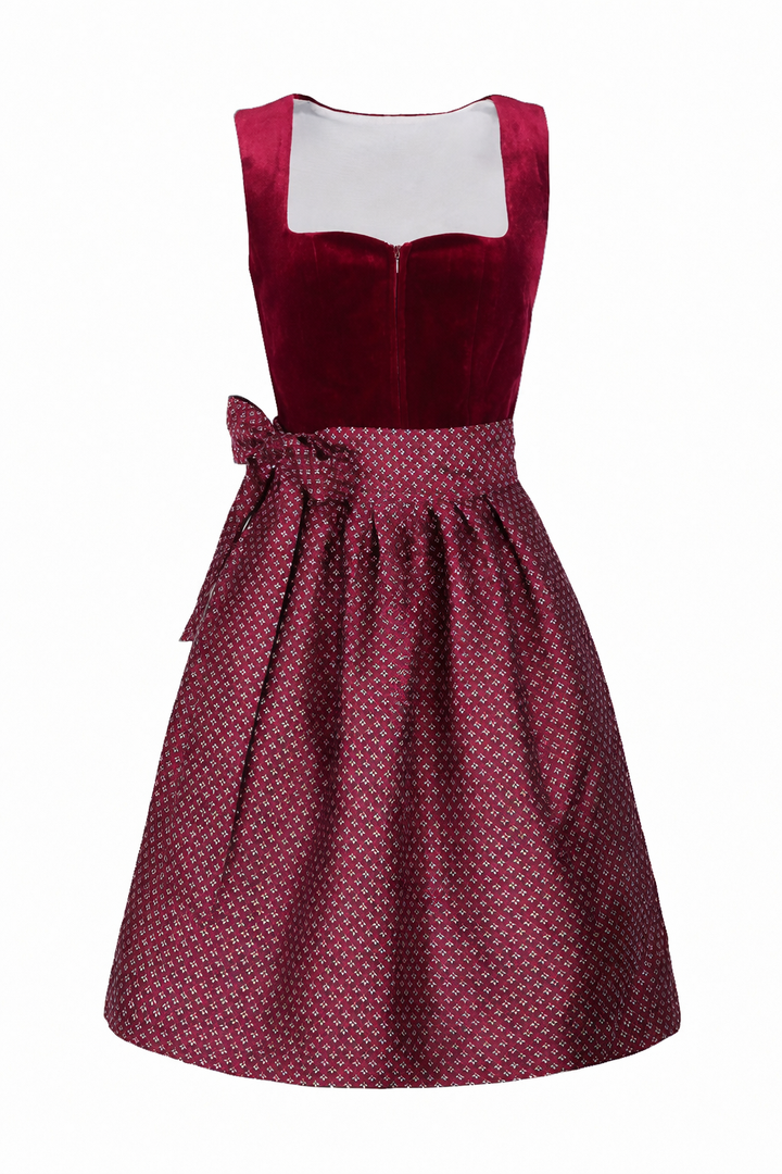 Dirndl bordeaux vu de face, corsage en velours à encolure carrée et tablier à motifs noué en nœud sur le côté. 1