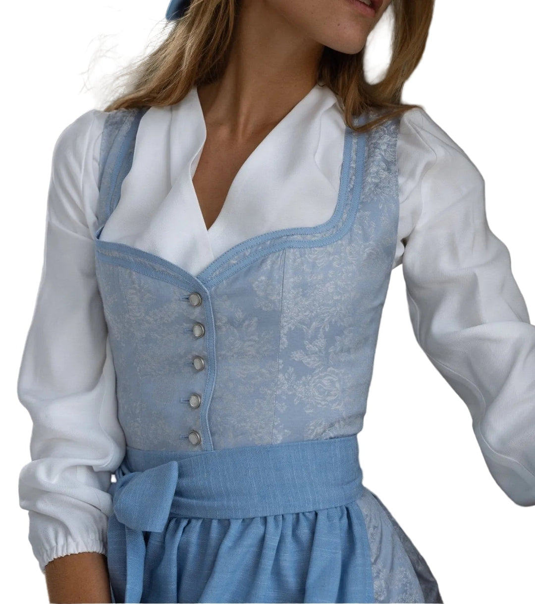 Femme portant le corsage bleu clair à motif floral sur un chemisier blanc, tablier noué à la taille, vue en buste de trois quarts. 1