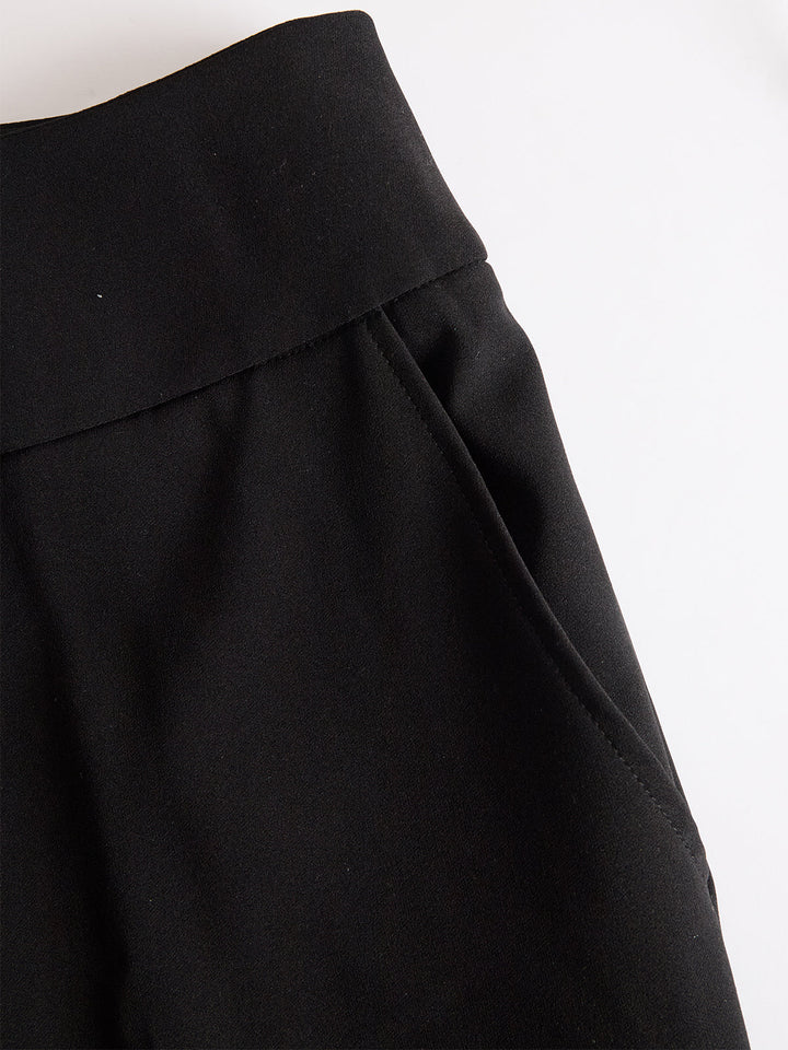 Gros plan à plat sur la ceinture large et la poche latérale du pantalon noir. 5