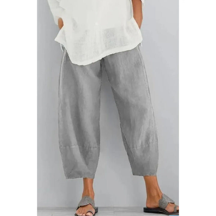 Pantalon large gris clair à taille élastique, porté avec une blouse blanche et des sandales tressées sur fond gris. 4