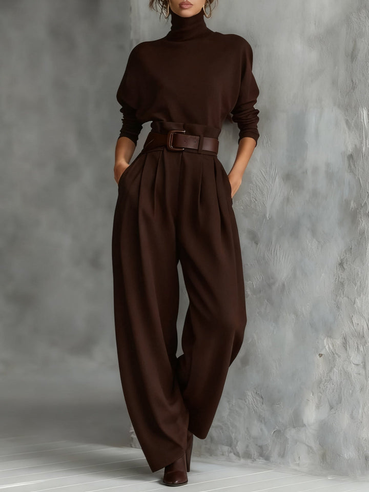 Ensemble marron foncé porté de face avec ceinture assortie, mains dans les poches, devant un mur texturé 5