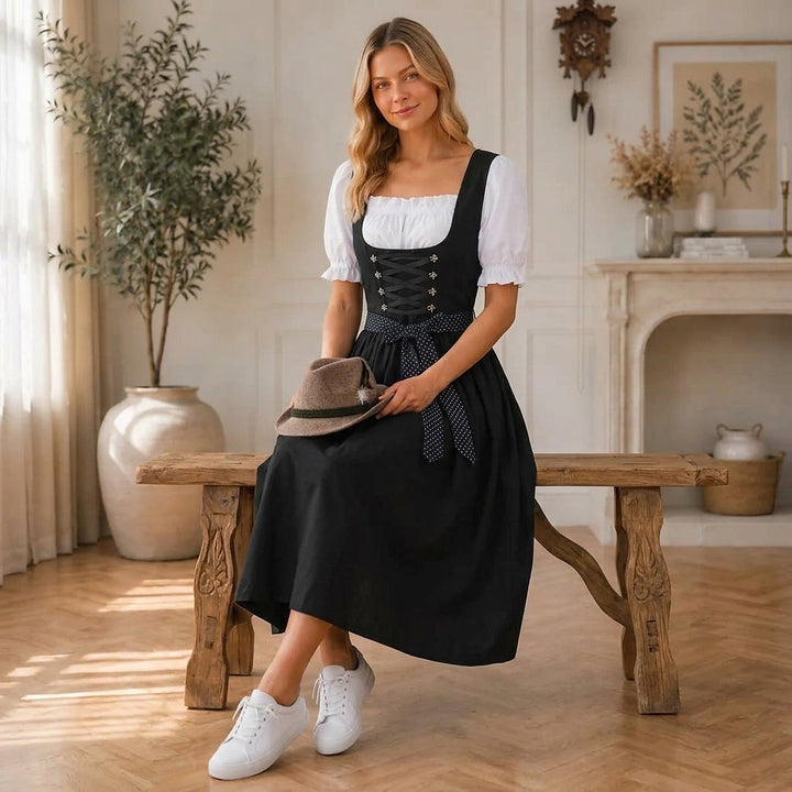 Femme assise sur un banc en bois, tenant un chapeau feutre, portant la robe noire à lacets et une blouse blanche. 3
