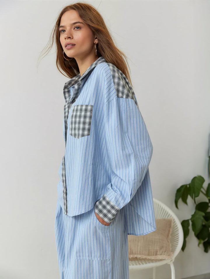 Mannequin de profil en pyjama bleu rayé avec poche, col et épaules à carreaux gris, devant une chaise blanche et une plante. 3