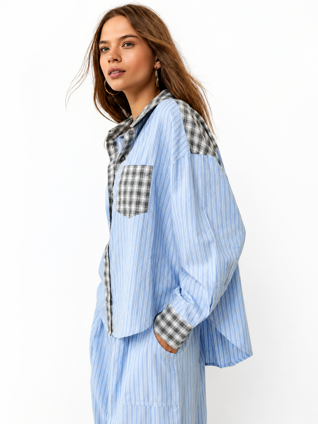 Chemise rayée bleu clair aux empiècements à carreaux gris, portée de profil par un mannequin sur fond blanc, une main dans la poche. 1
