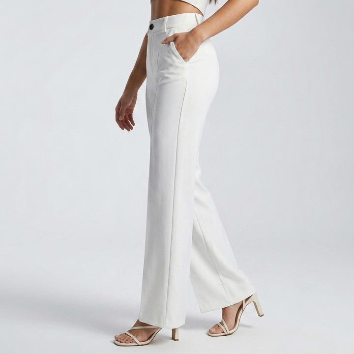 Pantalon blanc vu de profil, main dans la poche, jambe large et sandales à talons 4