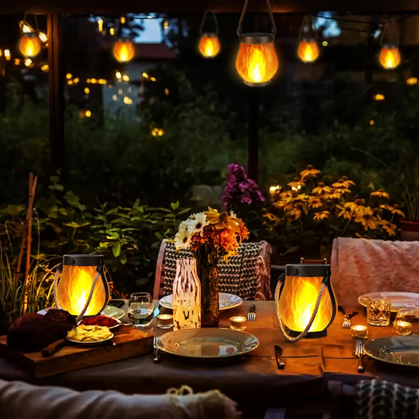 Lanternes allumées sur une table dressée et suspendues au-dessus, en soirée dans le jardin 7