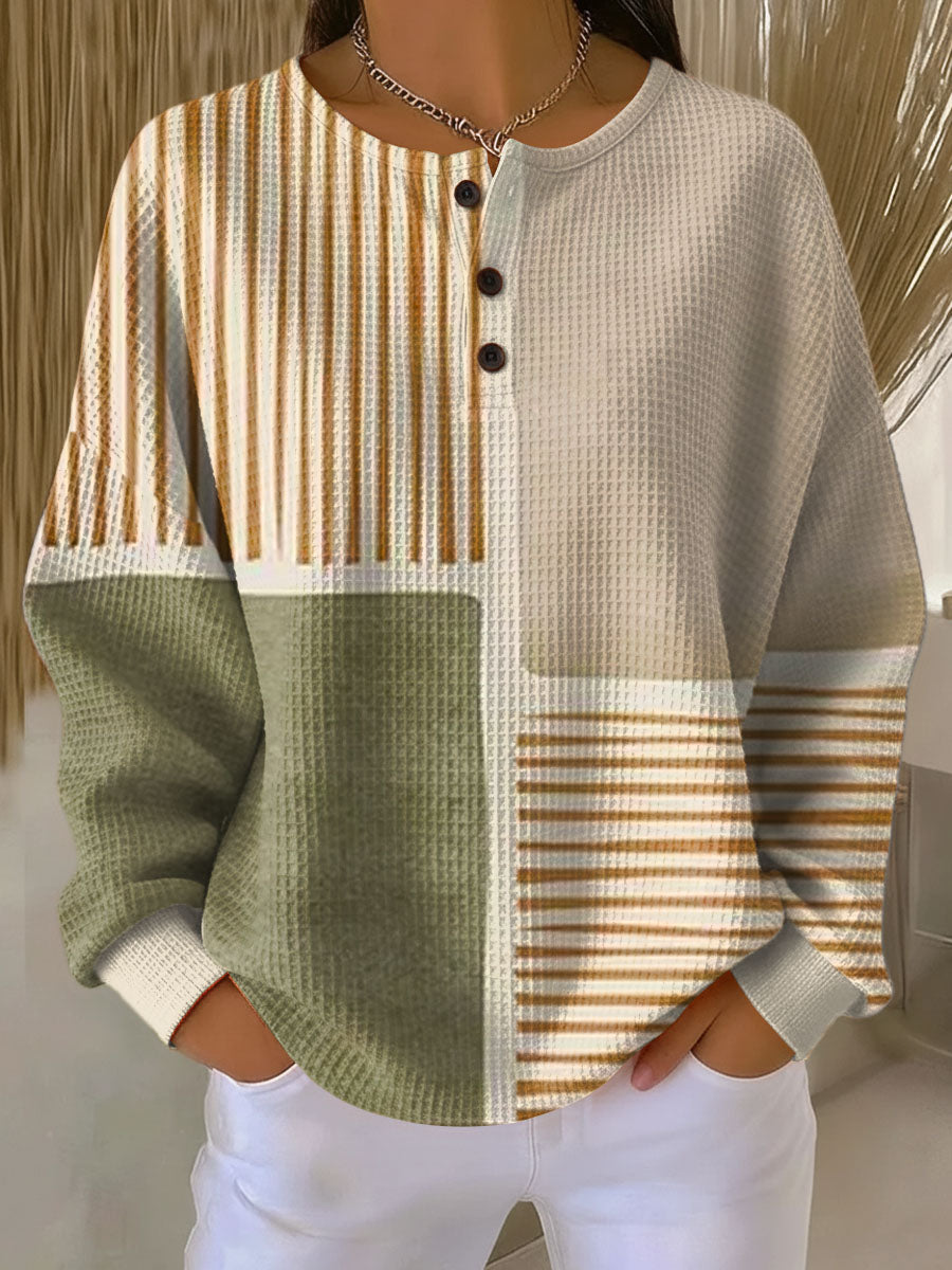 Pull gaufré à col tunisien porté avec un jean blanc, motif patchwork de blocs vert sauge, beige et rayures ocre. 1