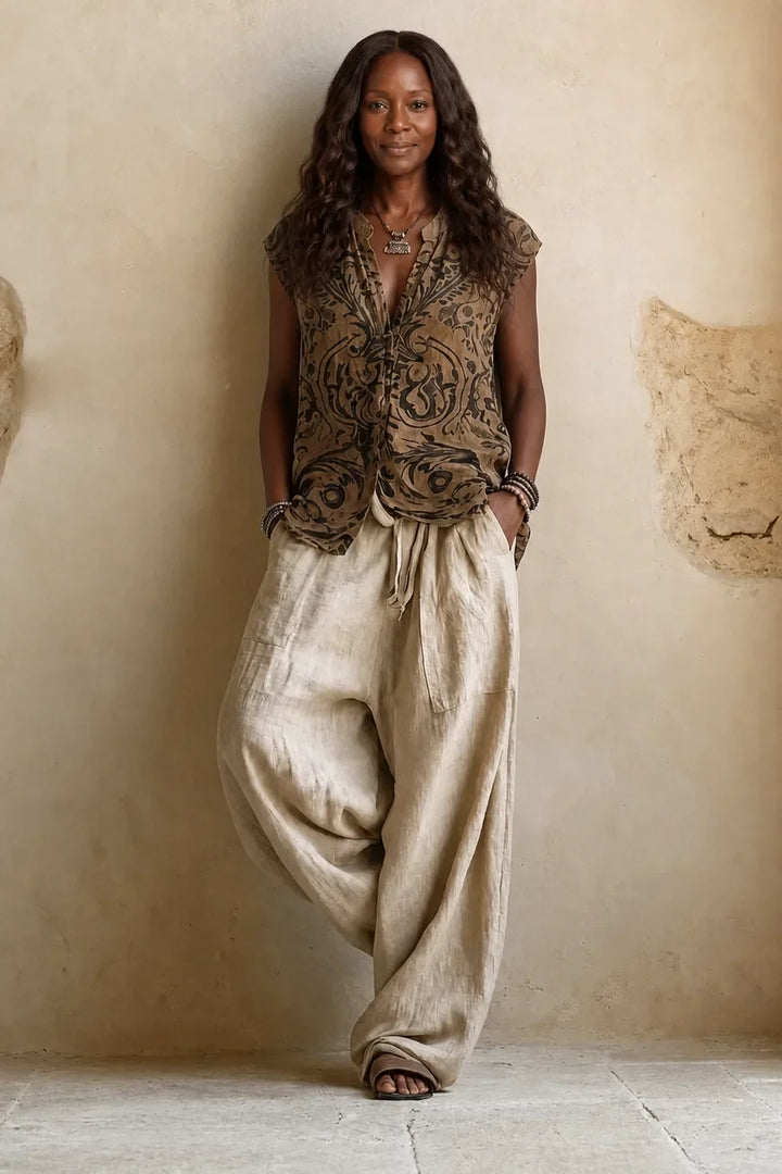 Femme de face sans le cardigan, en haut sans manches à motifs baroques bruns et noirs avec pantalon ample écru à cordon. 2
