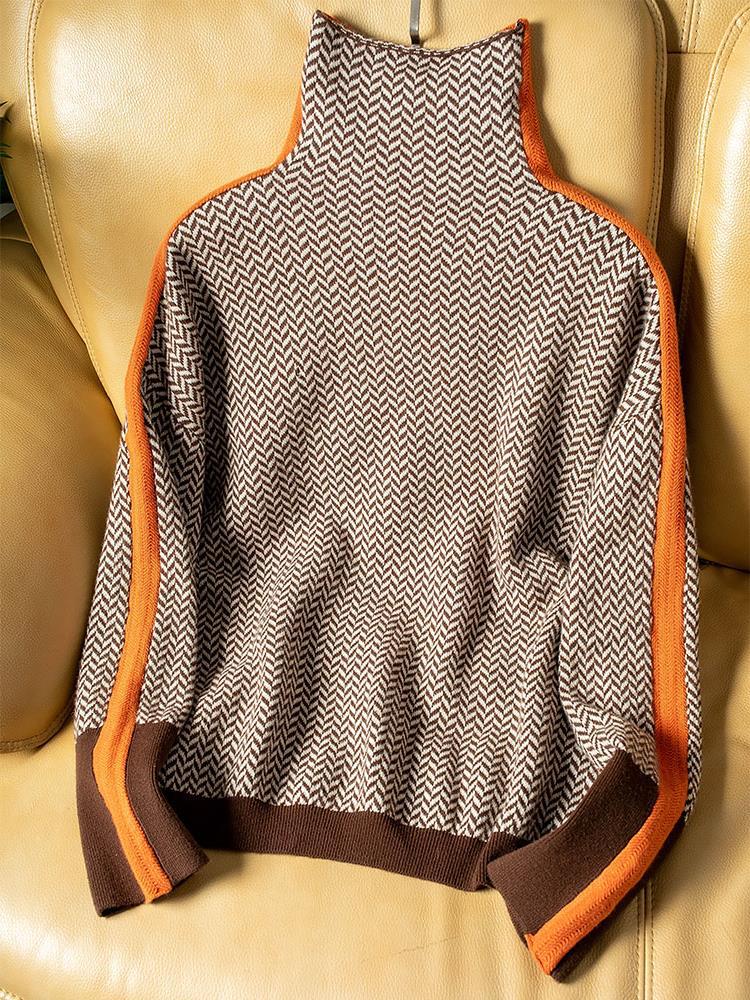 Pull à chevrons marron et beige posé à plat sur un fauteuil en cuir, liserés orange sur les épaules et manches. 5