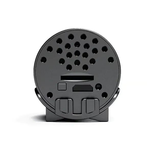 Face arrière de la caméra noire avec grille perforée, fente pour carte, port et bouton, sur son support. 10