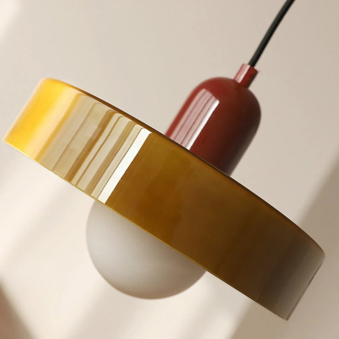 Gros plan en contre-plongée sur le bord épais du verre brillant jaune-vert, le capuchon rouge et le globe opalin. 28