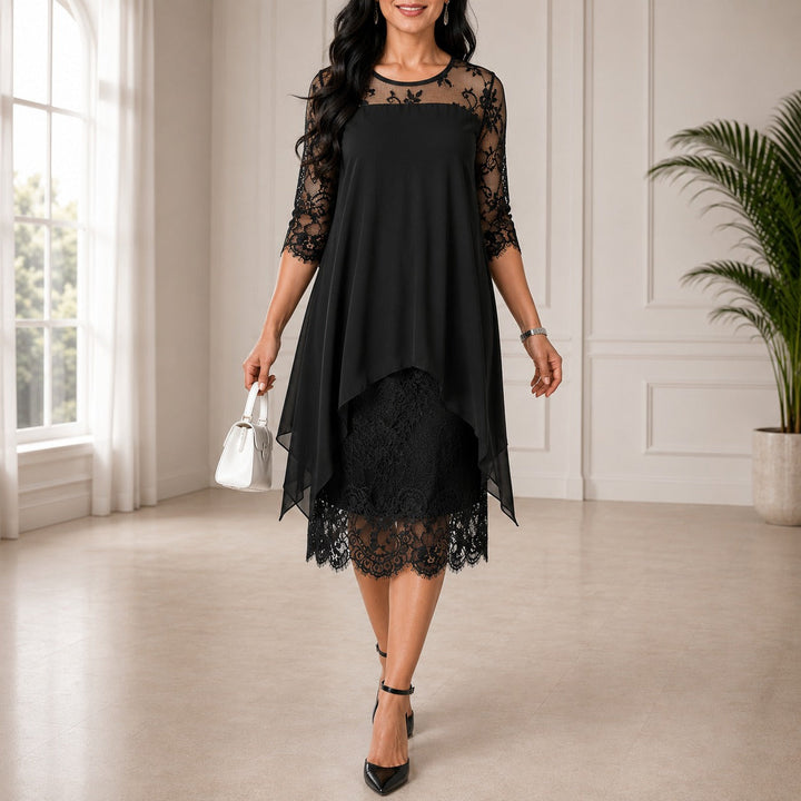 Version noire de la robe portée par une mannequin, empiècement et manches en dentelle, jupe asymétrique en voile, sac blanc et escarpins. 2