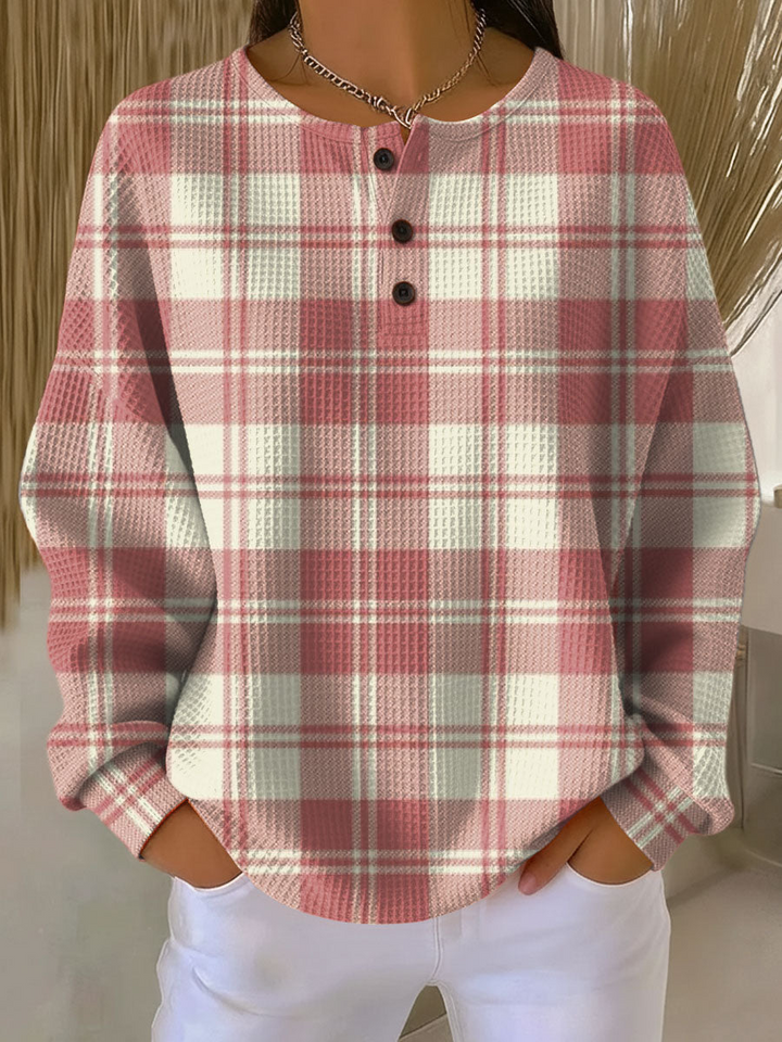 Pull gaufré à carreaux écossais rose et blanc cassé, col à trois boutons, porté avec un pantalon blanc. 15