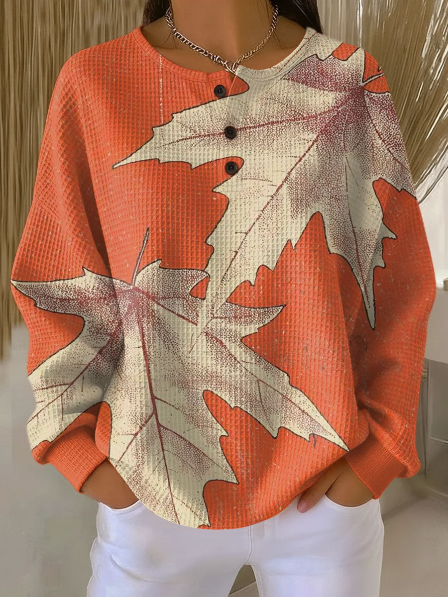 Pull gaufré orange imprimé de grandes feuilles d'érable beiges, col rond à trois boutons, vue de face. 14