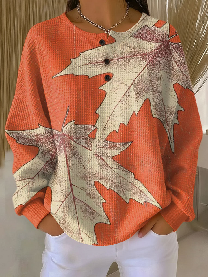 Pull gaufré orange imprimé de grandes feuilles d'érable beiges, col rond à trois boutons, vue de face. 14