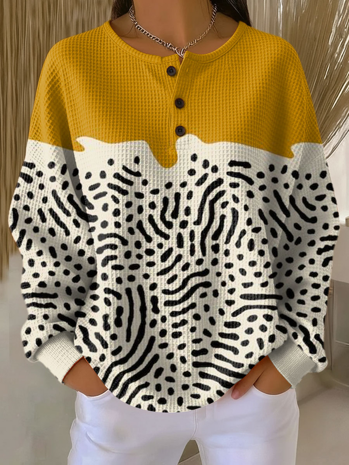 Pull gaufré à haut jaune moutarde et bas crème orné de motifs noirs en points et traits, trois boutons au col. 13