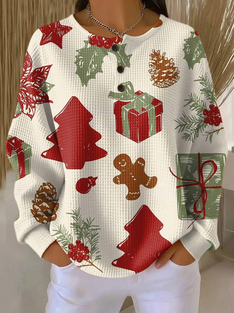 Pull gaufré crème à col boutonné porté avec un pantalon blanc, motif de sapins rouges, cadeaux, pommes de pin et bonhomme en pain d'épices. 23