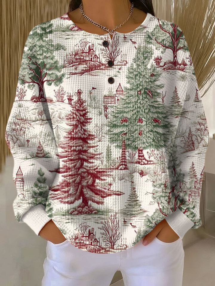 Pull gaufré blanc cassé à col boutonné, porté par une mannequin, motif de sapins verts et rouges et de maisons en campagne. 22