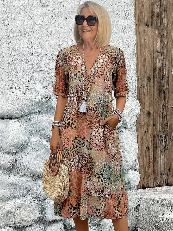 Robe à imprimé léopard multicolore dans des tons beige, orangé et vert, portée par une femme blonde en lunettes de soleil. 5