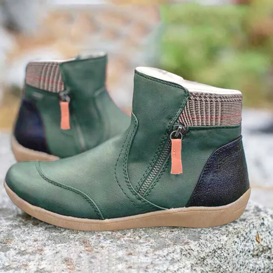 Paire de bottines vertes à fermeture éclair latérale, col en tissu à carreaux et talon noir, posée sur une pierre. 1