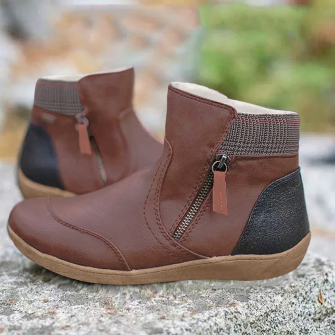 Paire de bottines marron à zip latéral, col en tissu à carreaux et contrefort noir, présentée sur un rocher. 3