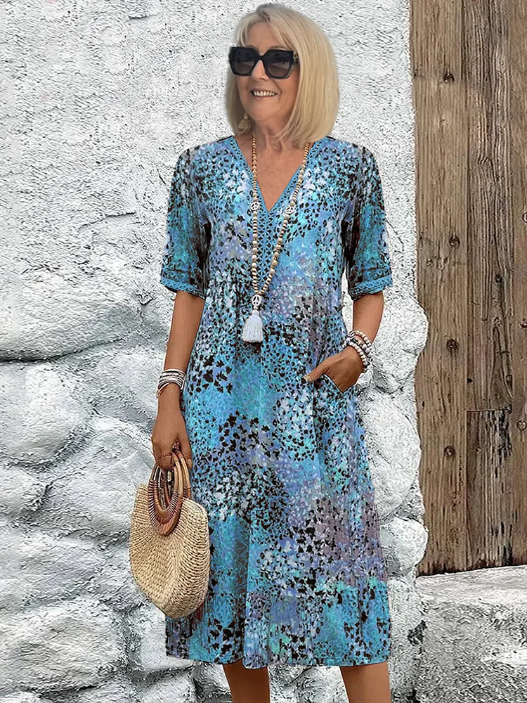 Même robe à manches courtes et col V en imprimé léopard bleu, portée avec un sac en paille devant un mur blanc. 2