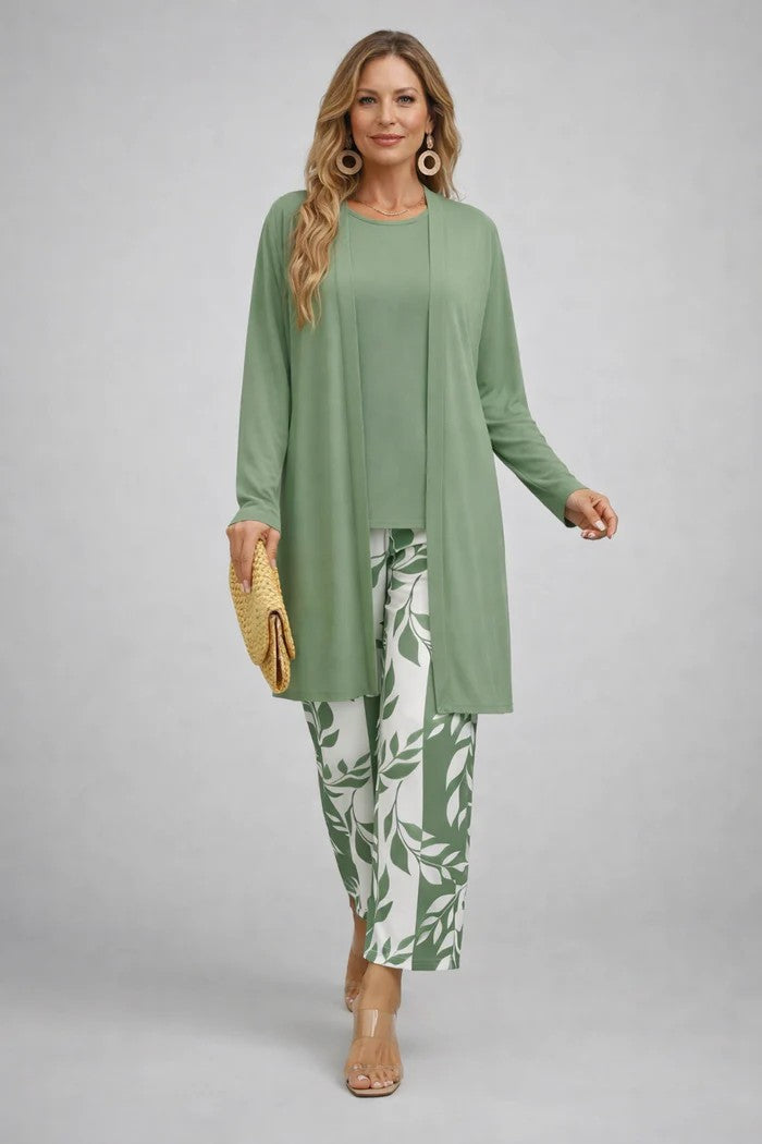 Femme en cardigan long et haut vert sauge unis, pantalon à feuillage vert et blanc, pochette en paille. 10