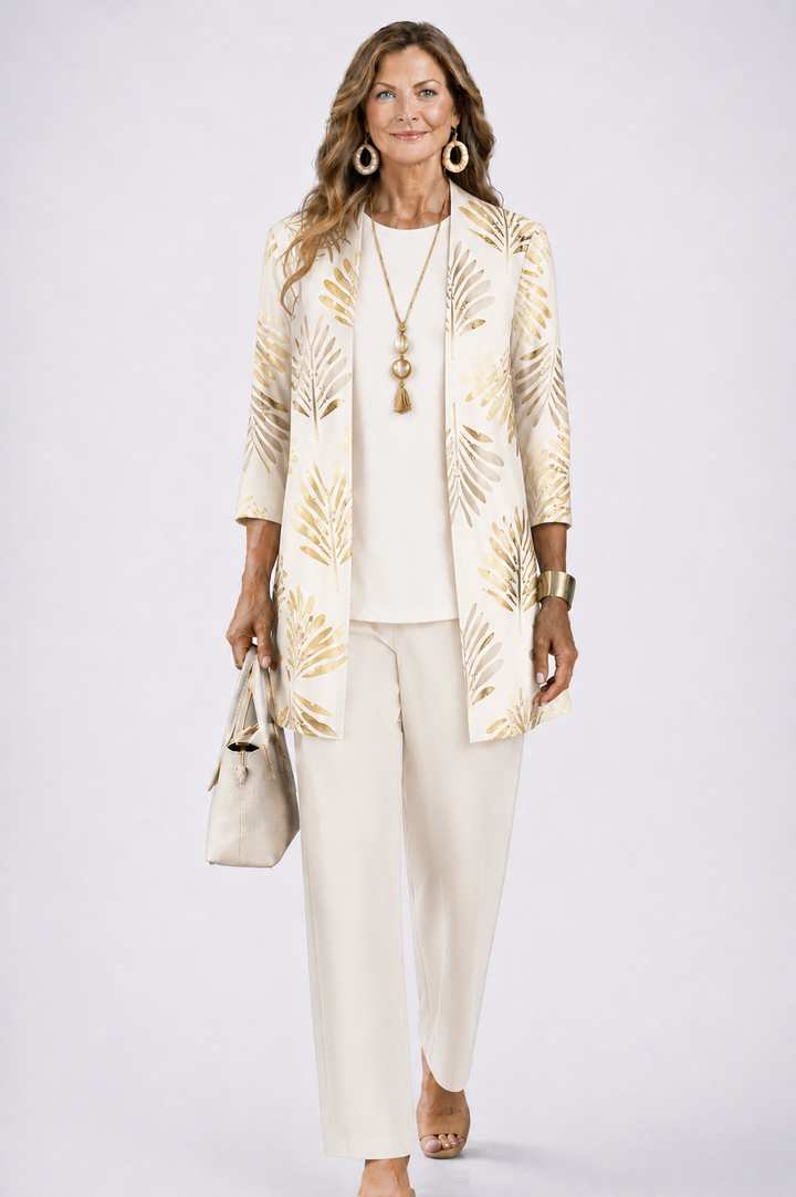 Femme en ensemble crème avec cardigan ouvert à motif de feuilles dorées, haut et pantalon unis assortis, sac clair. 3