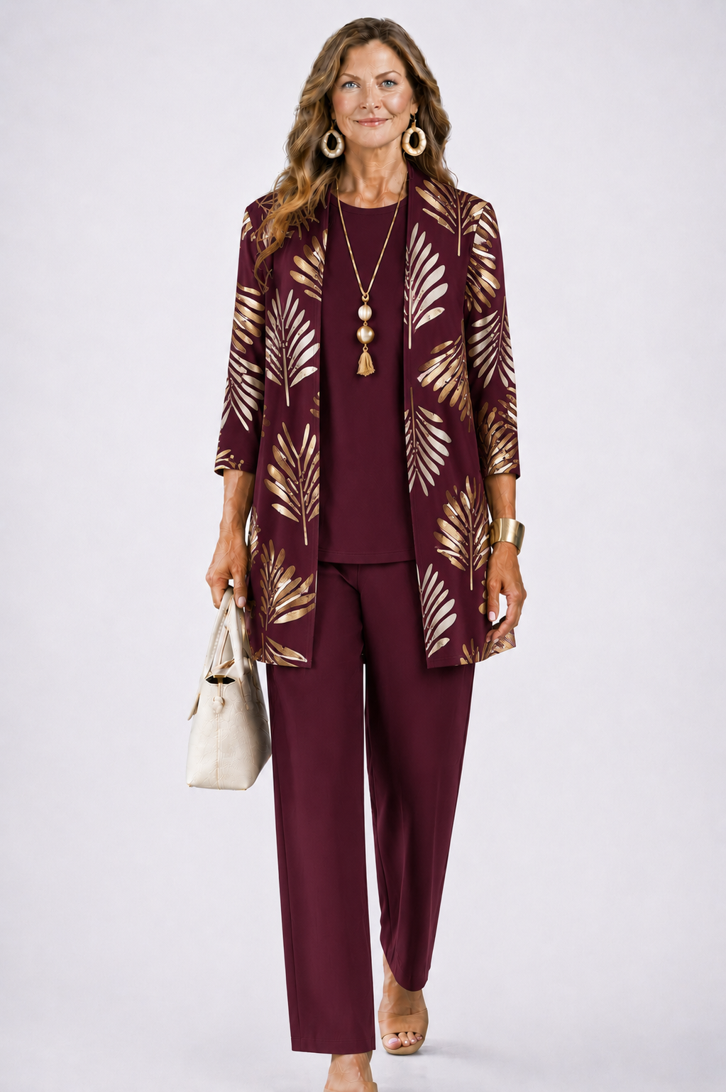 Femme en ensemble bordeaux, cardigan ouvert à feuilles dorées, haut uni et pantalon droit assortis. 6